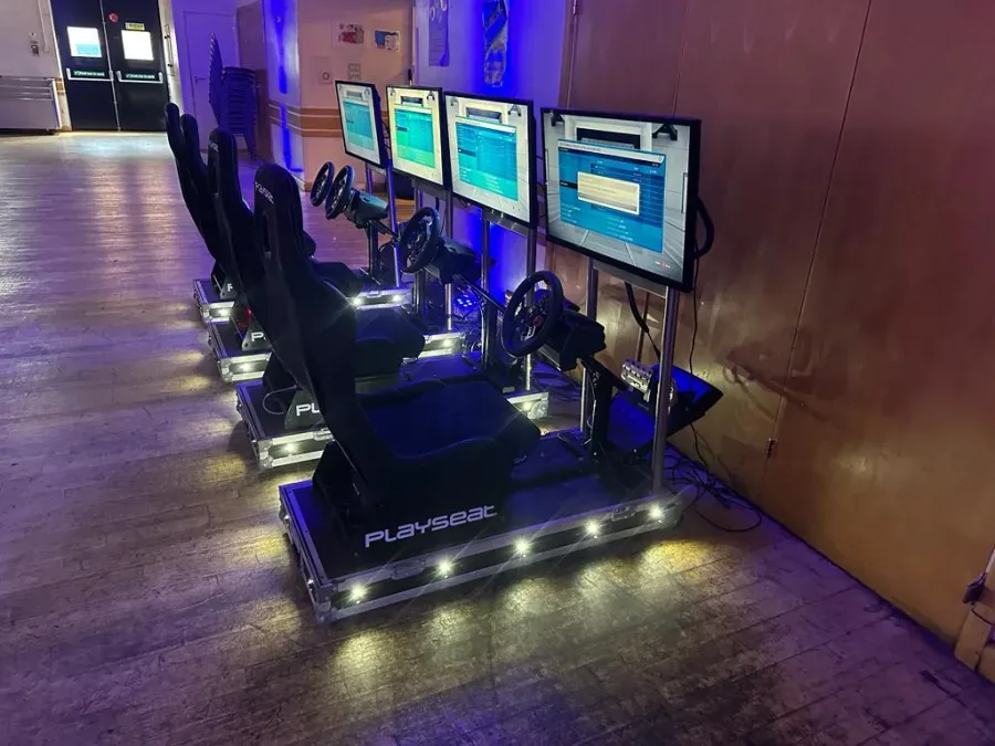 Racing sim rigs with LED-lit bases at an evening event