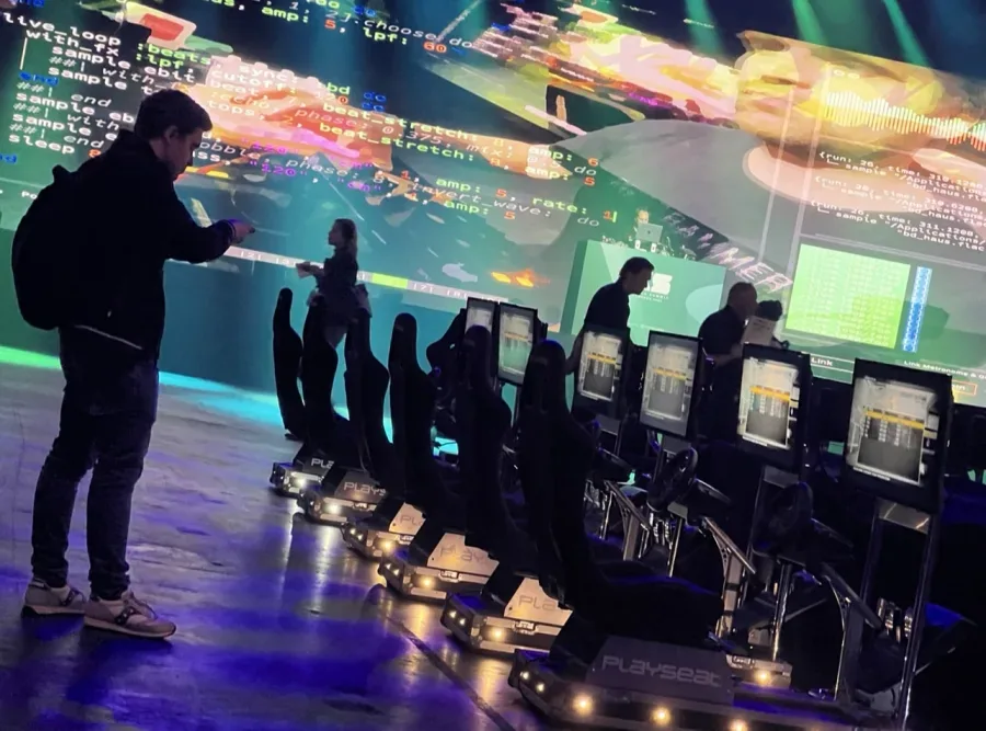 Row of F1-style simulators in front of a conference stage for a tournament